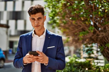 Genç adam parkta akıllı telefon kullanıyor.