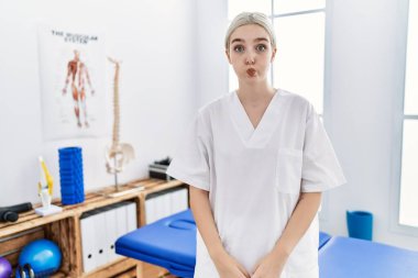 Ağrı kesici kliniğinde çalışan beyaz bir kadın komik suratıyla yanaklarını şişiriyor. Havayla şişmiş ağız, çılgın bir ifade.. 