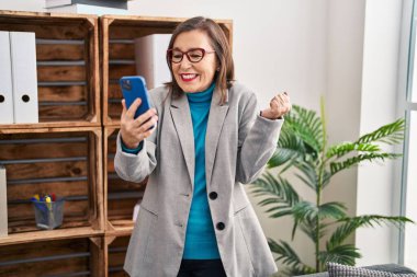 Orta yaşlı İspanyol kadın video çekiyor. Gururla bağırıyor, zaferi kutluyor ve kollarını kaldırarak başarıyı kutluyor. 