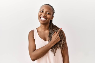 Saçları örgülü siyah bir kadın mutlu bir şekilde arka planda duruyor. Yüzünde mutlu ve doğal bir ifadeyle elleri ve parmaklarıyla yüzünü gösteren bir gülümseme var. 