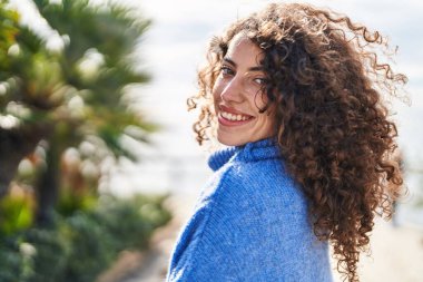 Parkta kendinden emin gülümseyen genç İspanyol kadın.