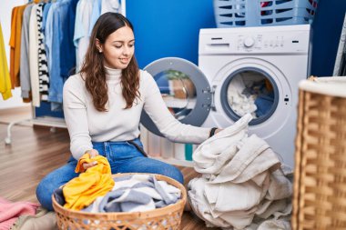 Genç, güzel İspanyol kadın gülümsüyor çamaşırhanede çamaşırları yıkayacak kadar kendinden emin.