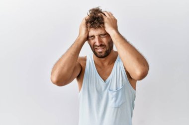 Genç yakışıklı adam izole edilmiş arka planda duruyor. Baş ağrısı, çaresiz ve stresli. Çünkü acı ve migren. Ellerini başının üstüne koy.. 