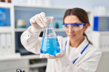 Laboratuvarda deney tüpü tutan bilim adamı üniforması giyen İspanyol genç bir kadın.