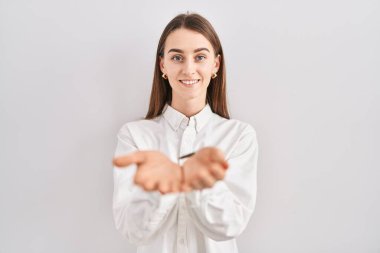 Young caucasian woman standing over isolated background smiling with hands palms together receiving or giving gesture. hold and protection 