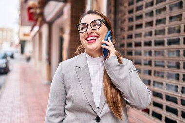 Young beautiful hispanic woman business worker smiling confident talking on smartphone at street