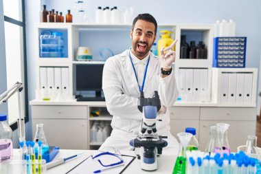 Sakallı, genç İspanyol bir adam. Laboratuvarda çalışıyor. Yüzünde kocaman bir gülümseme var.. 