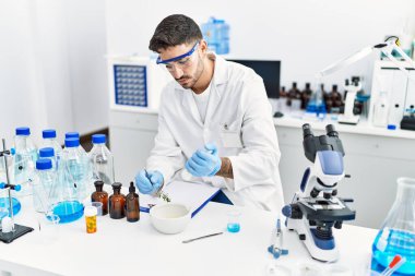 Laboratuvarda bilimsel havan topu kullanan yakışıklı İspanyol.