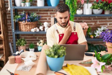 Çiçekçide dizüstü bilgisayar kullanarak konuşan İspanyol bir çiçekçi.
