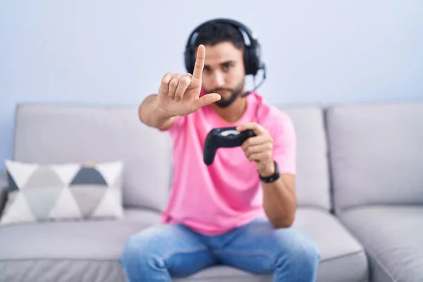 Jovem Hispânico Jogando Vídeo Game Segurando Controlador Sentado Sofá Apontando — Fotografia de Stock