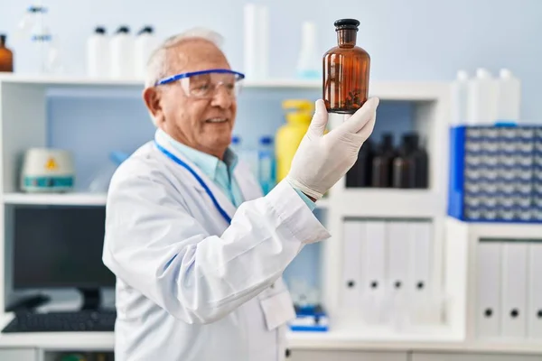 研究室で科学者の制服を着た先輩が瓶を持って — ストック写真