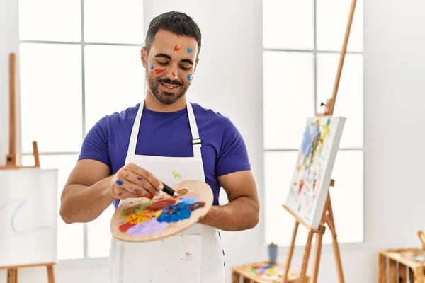 在艺术工作室的调色板上 年轻而惊慌失措的男人带着自信的笑容混合着色彩 — 图库照片