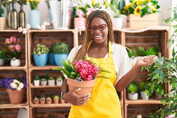 Mujer Afroamericana Con Cabello Trenzado Trabajando Floristería Sosteniendo Planta Gritando — Foto de Stock