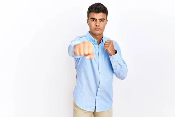 ビジネスシャツを着た若いヒスパニック系の男が孤立した背景パンチング拳の上に立って戦うために 積極的かつ怒りの攻撃 脅威と暴力 — ストック写真