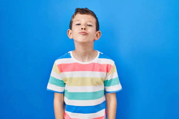 Joven Chico Caucásico Pie Sobre Fondo Azul Mirando Cámara Soplando — Foto de Stock