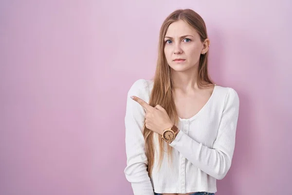 Ung Kaukasisk Kvinna Står Över Rosa Bakgrund Pekar Sidan Orolig — Stockfoto