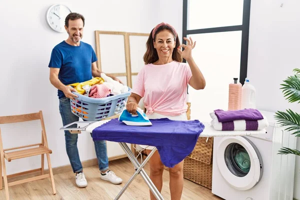 Medelålders Par Strykning Kläder Hemma Gör Tecken Med Fingrar Leende — Stockfoto