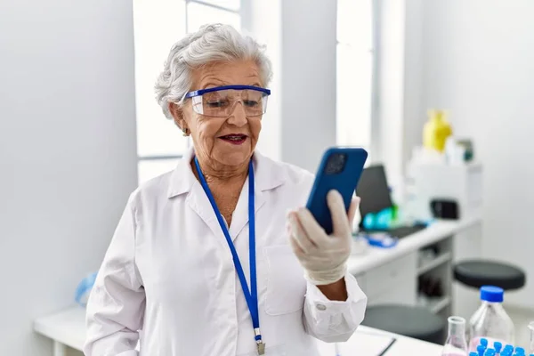 Starsza Siwowłosa Kobieta Mundurze Naukowca Używająca Smartfona Laboratorium — Zdjęcie stockowe