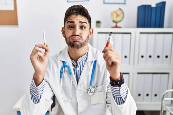 Young Doctor Man Holding Electronic Cigarette Medical Clinic Puffing Cheeks — Stock Photo, Image