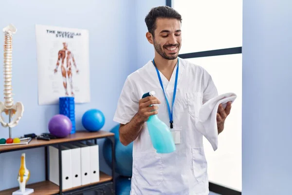 Young Hispanic Man Wearing Physiotherapist Uniform Holding Disinfection Sprayer Rehab — Stockfoto