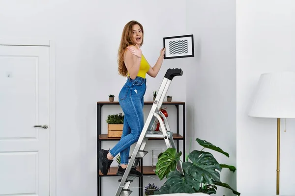 Young Caucasian Woman Stairs Hanging Picture Wall Celebrating Achievement Happy — Stock fotografie