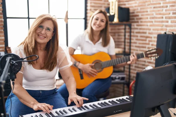 Mother and daughter playing classical guitar make selfie by the smartphone at music studio