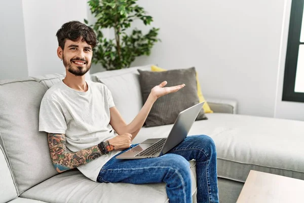 Homem Hispânico Com Barba Sentado Sofá Sorrindo Alegre Apresentando Apontando — Fotografia de Stock