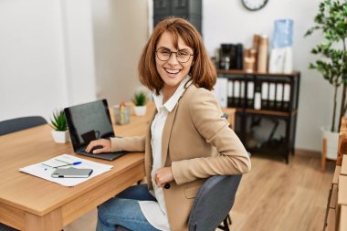 Ofiste çalışırken gülümseyen beyaz bir iş kadını..