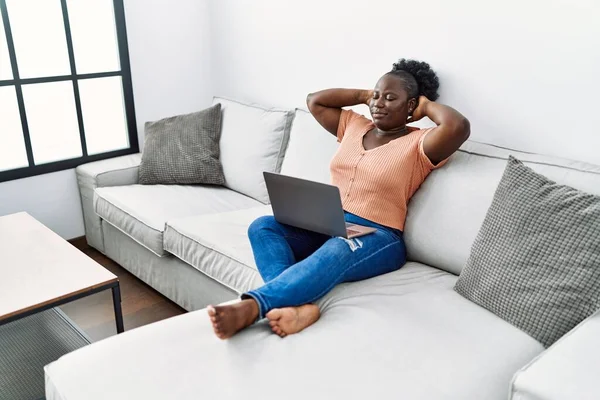 年轻的非洲裔美国女人在家里使用笔记本电脑 双手放在头上放松了下来 — 图库照片