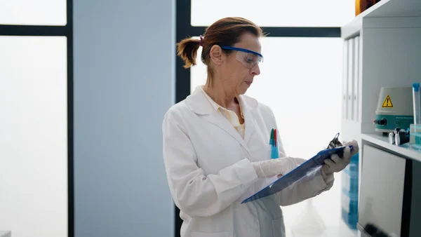 Μεσήλικας Ισπανίδα Γυναίκα Φορώντας Επιστημονική Στολή Κρατώντας Πρόχειρο Στο Εργαστήριο — Φωτογραφία Αρχείου