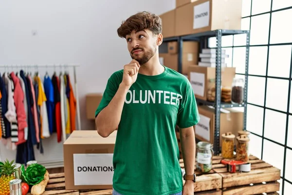 Junger Arabischer Mann Freiwilligen Shirt Spendenstand Die Hand Kinn Nachdenklich — Stockfoto