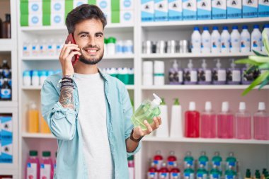 Genç İspanyol adam eczanede akıllı telefondan el ele tutuşup konuşuyor.