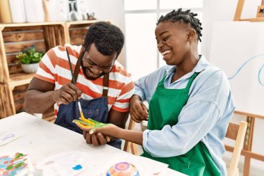 Afrikalı Amerikalı ressam çift gülümsüyor. Resim stüdyosunun masasında el ressamları oturuyor..