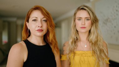 Evde ciddi bir ifadeyle yan yana duran iki kadın.