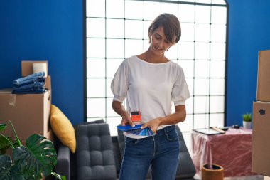 Young beautiful hispanic woman smiling confident holding test color at new home