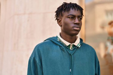 Afro-Amerikalı adam ciddi bir ifadeyle sokağa bakıyor.