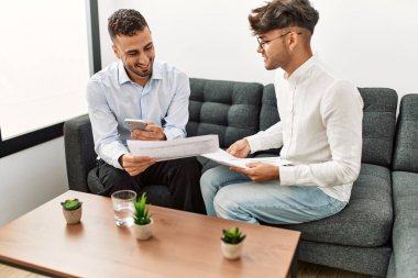 Two hispanic men business workers reading document working at office