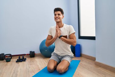 Spor merkezinde yoga eğitimi alırken gülümseyen İspanyol genç adam.