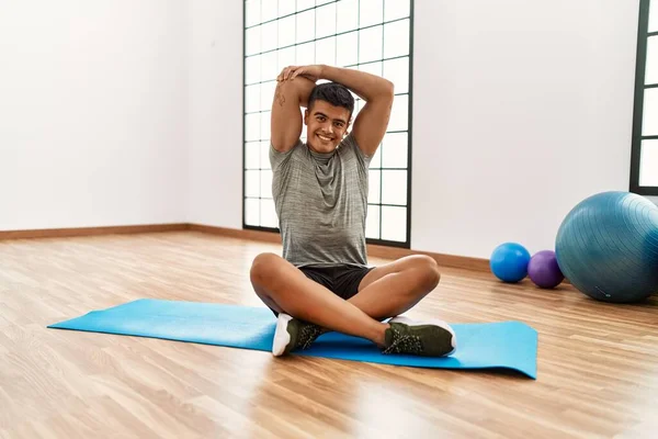 Joven Hombre Hispano Sonriendo Confiado Estirándose Centro Deportivo —  Fotos de Stock