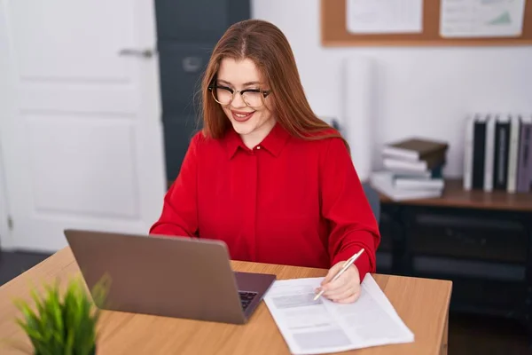 Genç Kızıl Saçlı Kadını Ofiste Dizüstü Bilgisayar Yazma Belgesi Kullanıyor — Stok fotoğraf