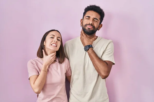 Young Hispanic Couple Together Pink Background Touching Painful Neck Sore — Stockfoto
