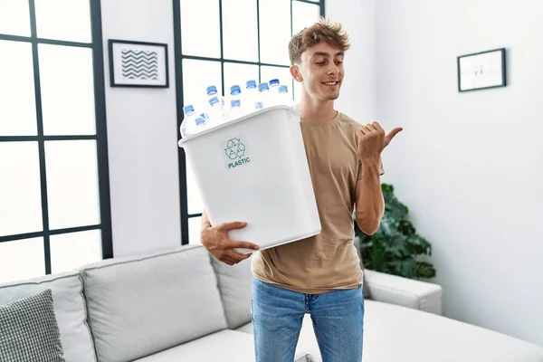 Young Caucasian Man Holding Wastebasket Recycling Plastic Bottles Home Pointing — Stock Photo, Image