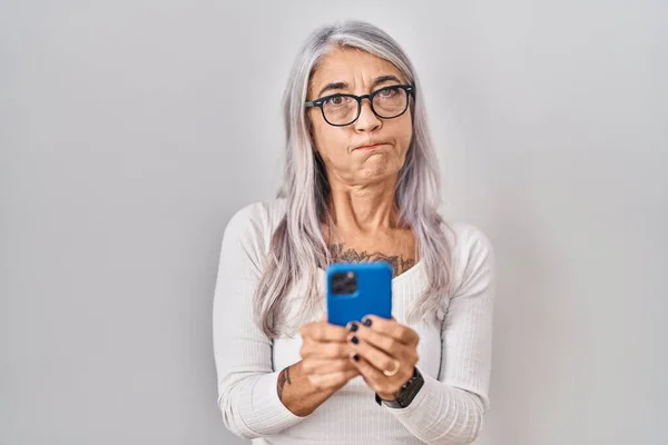 スマートフォンの入力メッセージを使用して白髪の中年の女性は面白い顔で頬をむき出す 空気を吸い込み空気を吸い込み — ストック写真