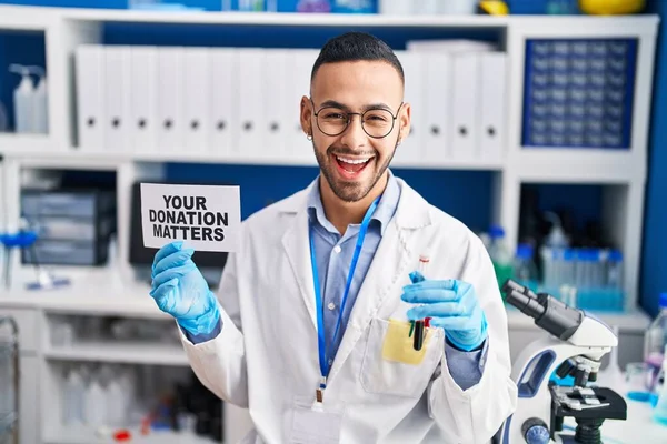 Young Hispanic Man Working Scientist Laboratory Holding Your Donation Matters — Fotografia de Stock
