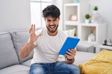 Sakallı İspanyol bir adam kanepeye oturmuş deli gibi bağırıyor ve bağırıyor. Saldırgan bir ifade ve kollar havada. hüsran kavramı. 