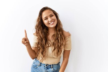 Güzel İspanyol kadın tek başına ayakta dikilirken arka plan bir numarayı gösterip işaret ederken kendinden emin ve mutlu bir şekilde gülümsüyor.. 