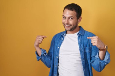 Sarı arka planda duran İspanyol adam kendine güvenen, yüzünde gülümsemeyle kendini gururlu ve mutlu olarak gösteriyor.. 