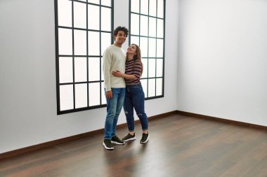 Genç İspanyol çift mutlu bir şekilde gülümsüyor ve boş yeni evlerinde birbirlerine sarılıyorlar..