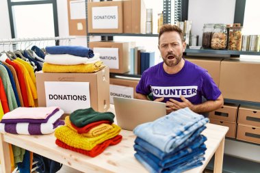 Orta yaşlı bir adam dizüstü bilgisayarı olan gönüllü bir tişört giyiyor midesi üzerinde çalışıyor çünkü hazımsızlık, acı veren bir hastalık kendini iyi hissetmiyor. Ağrı kavramı. 