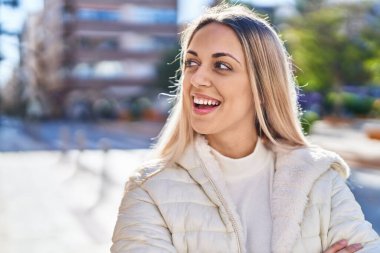 Kendine güvenen genç bir kadın caddede kollarını kavuşturmuş duruyor.